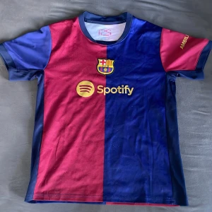 FC Barcelona Lamine Yamal matchtröja - Snygg FC Barcelona fotbollströja med Lamine Yamal 19-tryck. Tröjan har klassisk halva-röd halva-blå design, guldiga detaljer och klubbmärke på bröstet. Korta ärmar och tillverkad i lätt, ventilerande material. Perfekt för dig som älskar Barca och vill sticka ut på planen.