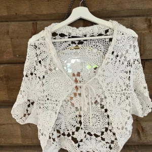 Vit virkad bolero - Superfin vit virkad kofta från Fransa i storlek M (jag är XS och passar mig). Koftan har korta ärmar, knytning framtill och ett vackert spetsmönster. Perfekt att slänga över en topp eller klänning