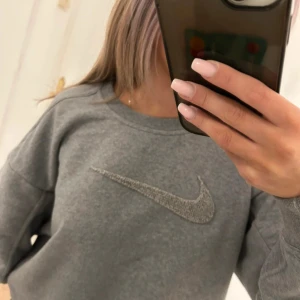 Grå Nike sweatshirt med logga XS - Säljer en grå sweatshirt från Nike i storlek XS. Tröjan har en klassisk rund halsringning och är dekorerad med en stor broderad Nike-logga framtill. Tillverkad i mjuk bomulls- och polyestermix för en skön och avslappnad passform. Perfekt för en chill och sportig look.❤️