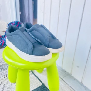 Svarta slip-on sneakers med vit sula - Stilrena svarta slip-on sneakers med tjock vit platt sula. Skorna har en minimalistisk design utan snörning och är tillverkade i ett mjukt tygmaterial. Perfekta för en avslappnad och trendig look.