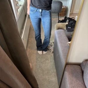 Blå bootcut jeans med broderad ficka - Snygga blå jeans med bootcut passform och coolt broderad bakficka. Jeansen har klassisk femficksdesign, normal midja och är tillverkade i stretchigt denim för skön passform. Perfekta för dig som gillar en tidlös men trendig look.