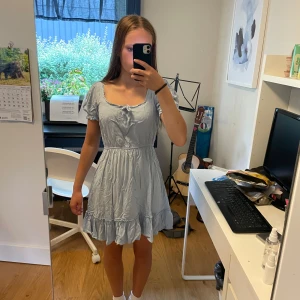 Ljusblå kortklänning från NA-KD - Supersöt ljusblå kortklänning från NA-KD med puffiga korta ärmar och söt rosett vid urringningen. 