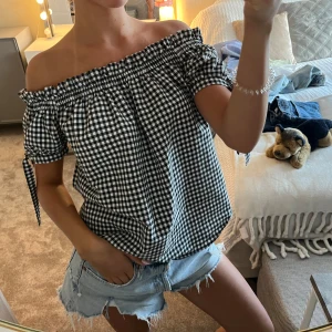 Offshoulder rutig topp med knyt - Säljer denna jättegulliga svartvit offshoulder topp med rutigt mönster och korta ärmar med knytband💕💕
