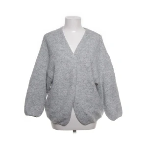 Lindex kofta grå - Mysig och oversized grå stickad kofta med v-ringad hals och långa ärmar. Perfekt för lager-på-lager och chill dagar. Koftan har en enkel design utan knappar eller dragkedja och är riktigt skön att slänga på sig när det är kallt.
