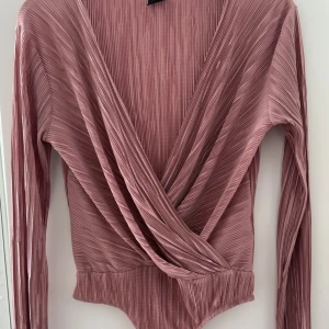 Rosa omlottopp från Gina Tricot - Säljer en snygg rosa omlottopp från Gina Tricot med långa ärmar.