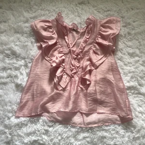 Rosa volangblus från Kappahl - Supersöt ljusrosa blus från Kappahl med volanger längs axlar och bröst, aldrig använd original pris var 400kr