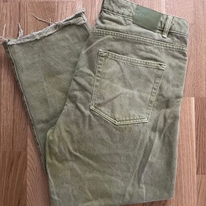 Gröna jeans från Pull&Bear med rå kant - Snygga gröna jeans från Pull&Bear i klassisk femficksmodell. Jeansen har råa, fransiga benslut för en avslappnad vibe och är tillverkade i bomull. Perfekta för dig som gillar en lite mer streetig stil.