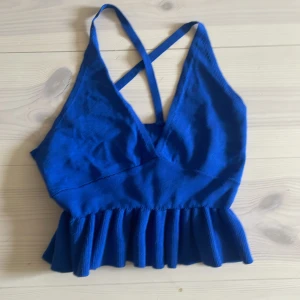 Blå croppad topp med volang från SHEIN - Snygg blå croppad topp från SHEIN med volangkant nedtill och smala axelband som korsas i ryggen.