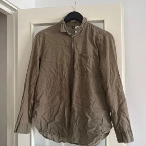 Beige henley-skjorta  - Säljer en beige henley-skjorta från Indiska i storlek 38. Skjortan har lång ärm, knappar vid halsen och bröstficka. Tillverkad i ett lätt och luftigt linnematerial, perfekt för en avslappnad och stilren look.