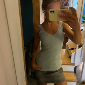 Ljusgrön ribbad linnetopp med spets - Supersöt ljusgrön ribbad linnetopp med v-ringning och spetsdetaljer längs urringningen och axelbanden. Sitter tajt, väldigt stretchig, perfekt till jeans eller kjol. Köpt från oklart märke i Tyskland. Super snygg!!🦋💕