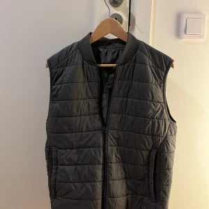 Grå väst från Zara S - Snygg grå dunväst från Zara med quiltad design och dragkedja framtill. Västen har en stilren, rak passform och ribbad krage. Perfekt att slänga över en hoodie eller tröja för extra värme. Fickor på sidorna och lätt vadderad känsla.Öppen för bundles och frågor!  Man, kille, grisch, Stockholm, plagg, billigt, small, s, stil, stiligt, style, jacka, tröja, skjorta, kvalitet, märke, märkeskläder