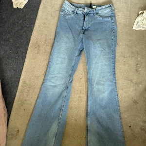 Ljusblå bootcut jeans i storlek 42 från hm  - Säljer ett par ljusblå jeans med bootcut-modell och klassisk femficksdesign. Jeansen har hög midja och är tillverkade i mjukt denimtyg. Perfekta för dig som gillar en retro vibe och vill ha ett par jeans med lite vidare ben.