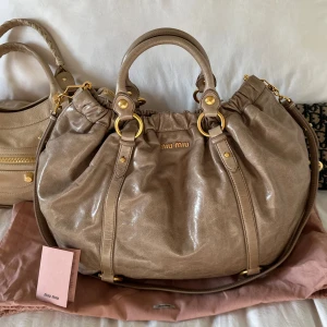 Så snygg Miu Miu Vitello med gulddetaljer - 🤍Billigare via vinted @juliavallberg pga höga avgifter på plick🤍 Säljer min Miu Miu-väska i modellen Vitello Shine mjuk beige/brun färg med varm underton. Välbervarade gulddetaljer. Väskan är i väldigt fint skick och kommer med original dustbag och äkthetskort (se bild). Väldigt lite använd. Endast en liten fläck som knappt syns. Ren invändigt och perfekta gulddetaljer. Mått: cirka 50x40 cm (oval rund form) Perfekta skol eller jobbväskan då den rymmer mycket utan att se otymplig ut🤍