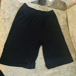 Svarta mjuka shorts  - Svarta shorts med elastisk midja och fickor. Tillverkade i mjuk och tunn viskosblandning med lite stretch för extra komfort. Perfekta för chill dagar eller när du vill ha något enkelt och bekvämt på dig.