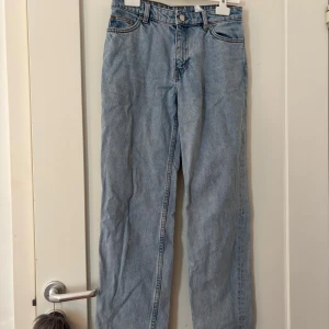 Ljusblå raka jeans från Monki - Säljer ett par ljusblå jeans från Monki i klassisk rak modell. Jeansen har fem fickor, bälteshällor och stängs med knapp och dragkedja. Tillverkade i 100% bomull för en skön och autentisk denimkänsla.