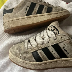 Beige Adidas Campus sneakers mocka - Snygga Adidas Campus sneakers i beige mocka med svarta ränder och vit sula. Väldigt använda därav pris, tänkte bara kolla om nån vill köpa å kanske snygga till eller tvätta? Nypris 1199