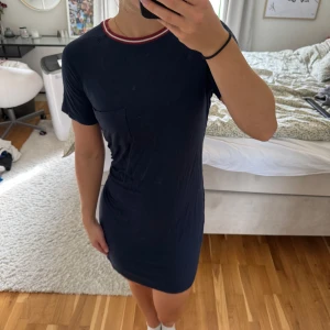 Mörkblå t-shirtklänning Abercrombie - Mörkblå t-shirtklänning från Abercrombie & Fitch med kort ärm, liten bröstficka och ribbad rund halsringning med röda och vita ränder. Skön bomullskänsla och avslappnad passform💗