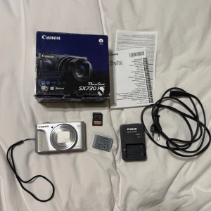 Canon PowerShot SX730 HS - Canon PowerShot SX730 HS är en kompaktkamera med 40x optisk zoom, 20,3 MP och vinklingsbar skärm – perfekt för vlogg, resor och äventyr. Inkluderar laddare, batteri och 64GB minneskort. Smidig att ta med överallt och enkel att använda för snygga bilder och videos. Kan mötas oxå.