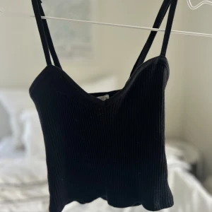 Svart ribbad linnetopp med smala band - Säljer en svart ribbad linnetopp med smala axelband och snygg v-ringning. 