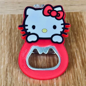 Söt rosa kapsylöppnare med Hello Kitty-motiv! - Söt röd kapsylöppnare med Hello Kitty-motiv & magnet på baksidan. Höjd: 7 cm. Oanvänd.