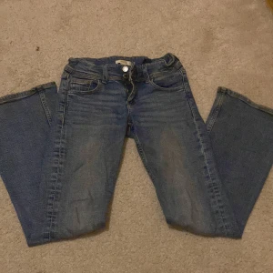 Blå bootcut jeans med låg midja - Säljer ett par blå jeans med bootcut och låg midja. Jeansen har klassisk femficksdesign, knappar på bakfickorna. Jag har sprett bort över delen på fickorna för att göra en mer cool design ❣️❣️