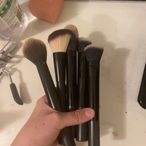 Set med sminkborstar i svart - Fem olika sminkborstar med svarta handtag och mjuka borst i olika former och färger, perfekt för applicering av puder, rouge eller contour. Borstarna har täta och fluffiga strån i beige och brunt. Snyggt och stilrent set för dig som vill ha en komplett basuppsättning.