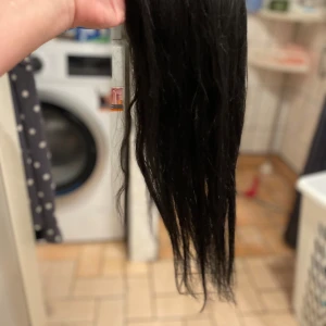 Svart löshår topp med clips - Säljer en svart hårtopp med clips som enkelt fästs i håret. Håret är långt, rakt till lätt vågigt och mäter ca 55 cm. Basen är av nätmaterial med flera clips för säker passform. Perfekt för att ge extra volym och längd till din frisyr. Äkta hår så klart 