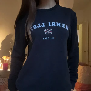 Mörkblå tröja från Henri Lloyd - Säljer en mörkblå långärmad tröja från Henri Lloyd med tryckt logga och brittisk flagga på bröstet. Nypris ligger på ungefär 500kr💞