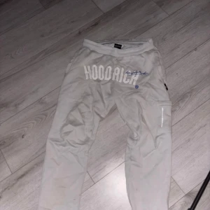 Vita mjukisbyxor från Hoodrich - Snygga vita mjukisbyxor från Hoodrich med broderad logga framtill och cool detalj på benet. Byxorna har avslappnad passform och resår i midjan för extra komfort. Perfekta för chill dagar eller streetwear-stil.