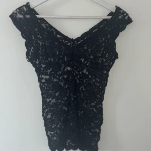 Svart spetsblus med v-ringning - Säljer en svart blus i spets med v-ringning och korta ärmar. Den är köpt på Zara för ungefär ett år sedan