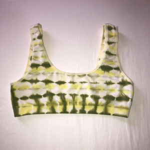 Gul och grön tie dye bh från Weekday - Säljer en snygg bh från Weekday i storlek L. Toppen har ett gult och grönt tie dye-mönster och breda axelband. 