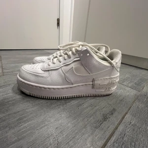 Nike Air Force 1 Shadow vita sneakers - Säljer ett par vita Nike Air Force 1 Shadow sneakers med klassisk design och dubbla detaljer på sulan, använda max 4 gånger. 
