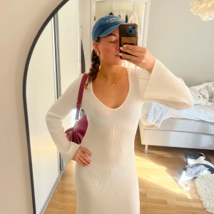 Vit ribbad långklänning med v-ringning - Säljer en vit långklänning med v-ringning och lång ärm. Klänningen har en figurnära passform som framhäver siluetten. Perfekt för dig som gillar en stilren och enkel look! Såå fin med guldsmycken till!🥰