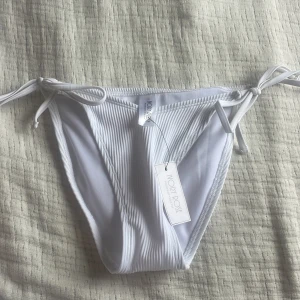 Vit ribbad bikiniunderdel  - Vit bikiniunderdel från Ivory Rose i storlek M/uk 8. Justerbar. 
