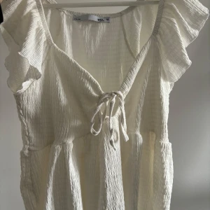 Vit blus med volangärm och knyt - Söt vit blus med volangärmar och knyt framtill. Blusen har en lätt rynkad struktur och v-ringad halsringning.  Säljer endast då jag ej använder den längre och behöver rensa garderoben! Knappt använd så den är i princip i nyskick! 