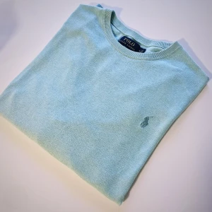 Ljusblå stickad tröja från Polo Ralph Lauren - Säljer en turkos stickad tröja från Polo Ralph Lauren i slim fit. Tröjan har rund halsringning, långa ärmar och den klassiska broderade loggan på bröstet. Tillverkad i mjuk pima bomull för extra komfort.Storlek M,Vid några frågor är det bara att höra av sig.