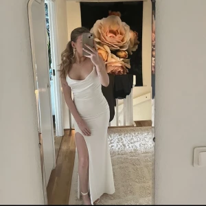 långklänning med slits och öppen rygg - Säljer en supersnygg bal/avslutningsklänning med smala axelband, draperad byst och hög slits framtill. Klänningen har en snygg öppen rygg och figurnära passform. Den är från showpo och ändast använd en gång!! Nypris 1400kr, mitt pris kan diskuteras💞🤌🏼