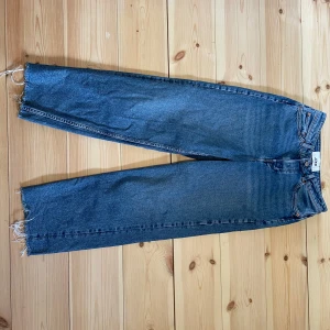 Blå raka jeans med råa kanter - Säljer ett par blå jeans från JJXX med raka ben och råa, fransiga benslut. Klassisk femficksmodell, mod waist och enkel design utan slitningar. Perfekta för en avslappnad och trendig look med exempelvis en snygg T-shirt 👌 Midjemått: 35cm Innerbenslängd: 68cm