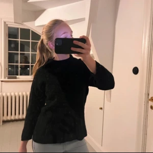 Svart stickad tröja med hög hals - En enkel och stilren svart stickad tröja med hög hals och långa ärmar.