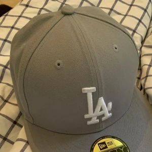 Grå LA-keps från New Era 59FIFTY - Säljer en stilren grå keps från New Era 59FIFTY den är använd 1 gång då jag testa den och den blev för liten helt äkta pris diskuteras