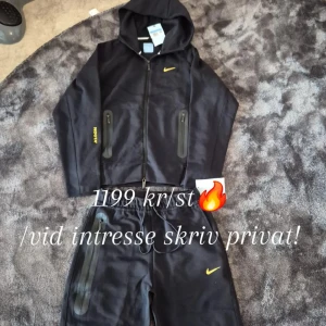 Nike*Nocta Tech - Säljer en svart tracksuit från Nike*NOCTA med gul logga. Setet består av en hoodie med dragkedja och huva samt matchande byxor med resår i midjan. Båda delarna har diskreta gula detaljer och dragkedjefickor.