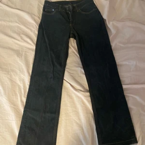 Mörkblå jeansbyxor från Vero Moda - Säljer ett par mörkblå jeansbyxor från Vero Moda med klassisk femficksdesign och kontrastsömmar. Byxorna har normal passform och raka ben, perfekt för en stilren look. Stängs med dragkedja och knapp framtill. Mid-midjade! 