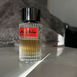 Moustache Eau de Parfum - Moustache Eau de Parfum från Rochas är en elegant herrdoft i en stilren, räfflad glasflaska med svart lock och röd etikett. Parfymen har en varm, bärnstensfärgad vätska och passar dig som gillar klassiska och sofistikerade dofter.
