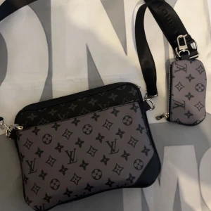 Grå axelväska - Snygg grå äxelväska, Väskan har justerbar axelrem och en mindre avtagbar ficka. Perfekt för att bära det viktigaste med stil.