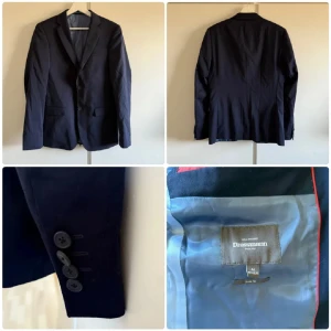 Mörkblå kostym - Säljer en stilren mörkblå kostym från Dressmann. En av knapparna på armen lite lös annars är den i bra skick. Kavajen är storlek 46R i slim fit och byxorna är 31/32 slim fit. En slips följer med på köpet också. 