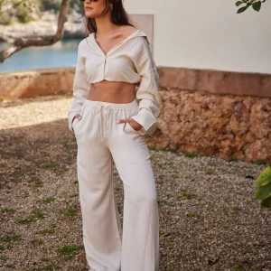 Nelly linnen set - Snygga och luftiga beiga linnebyxor med breda ben och resår i midjan. Perfekta för varma dagar och ger en avslappnad men trendig look. Matcha med en croppad topp för en stilren outfit. Byxa i storlek 36 och tröja i storlek 38