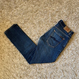 Nudie Jeans modell grim trim slim jeans - Snygga blå jeans från Nudie jeans, modell Grim Trim. Fint skick, förutom att de är lite slitna i grenen, bild kan skickas privat. Storlek 33/32, sitter nog lite mindre(ungefär 31/32),mått kan såklart skickas vid osäkerhet. 