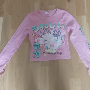 Rosa croppad långärmad tröja med anime-tryck från Zara - Säljer en rosa croppad långärmad tröja från Zara med färgglatt anime-inspirerat tryck och japansk text på framsidan. Nästan helt oanvänd!