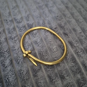 Guld armband i spikdesig - Säljer ett stol armband i guld med unik spikformad design. Armbandet har en modern stil, perfekt för dig som gillar statement-accessoarer. Enkel att öppna och stänga tack vare smart låsmekanism.