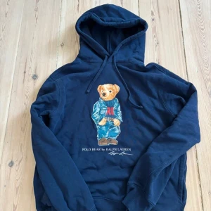 Mörkblå Polo Bear hoodie från Ralph Lauren - Säljer en mörkblå hoodie från Ralph Lauren med Polo Bear-tryck på bröstet. | Skick: 9 / 10 , väldigt sparsamt använd, inga fläckar, märken eller hål! | Nypris: 2200 | Vårt pris: 799 | Storlek: S | Tveka inte att höra av er med prisförslag eller funderingar!